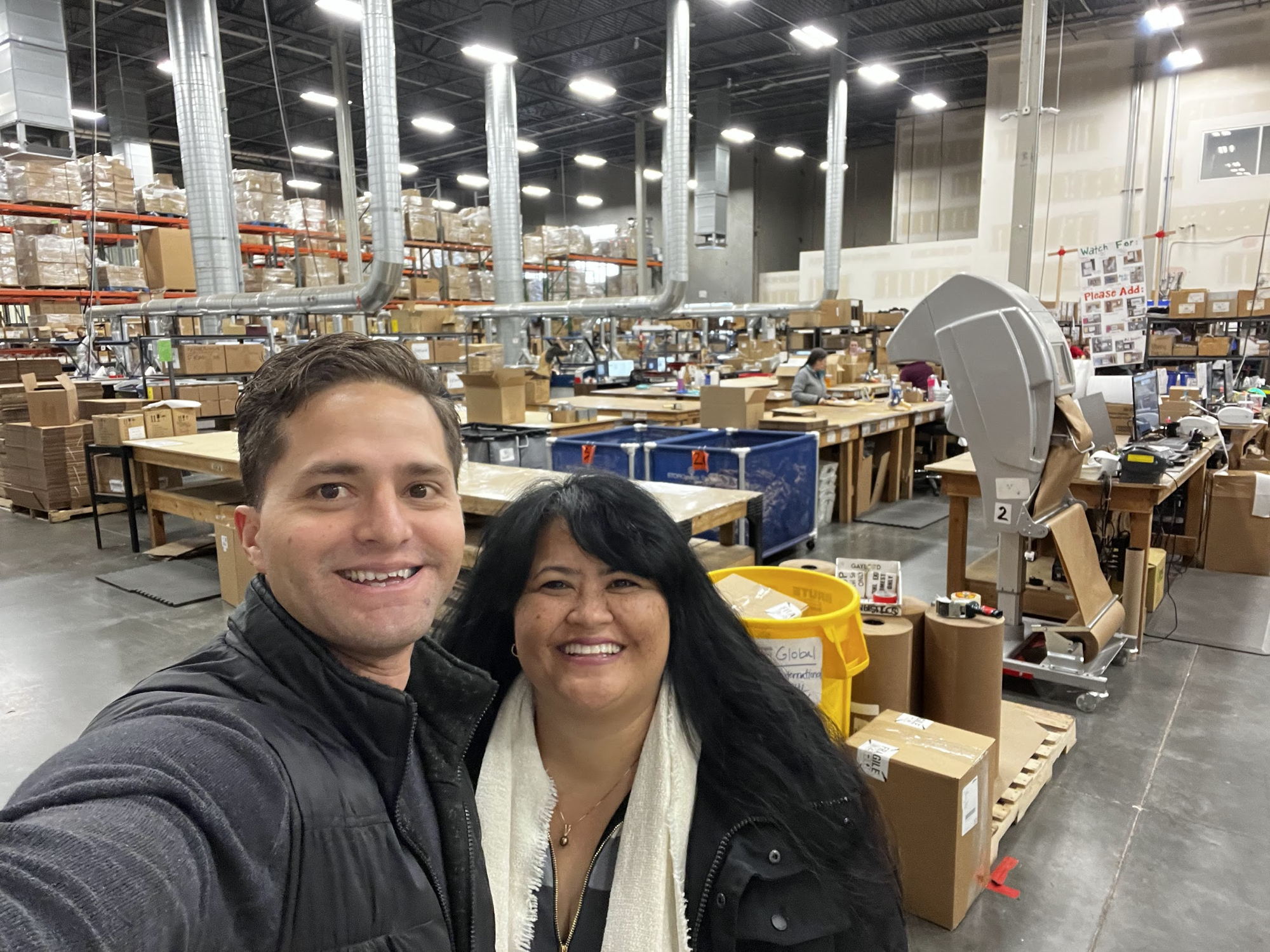 Reif in a fulfillment warehouse with a colleague, surrounded by packing stations and inventory